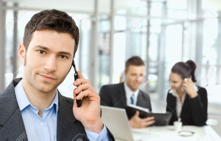 5100996-young-smiling-businessman-calling-on-phone-business-meeting-at-background-stock-photo